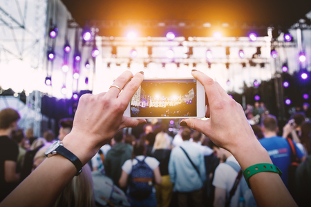 Using a mobile phone at outdoor summer music festivalの写真素材