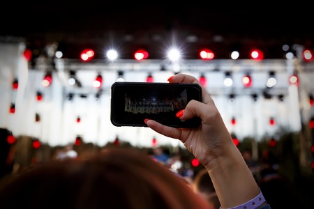 Using a mobile phone at a summer music showの写真素材