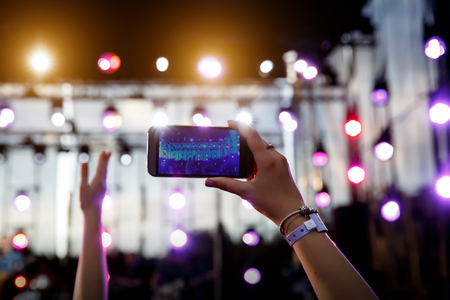Using a mobile phone at outdoor summer music festivalの写真素材