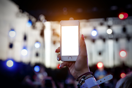 Using a mobile phone on a summer music show, blank screenの写真素材