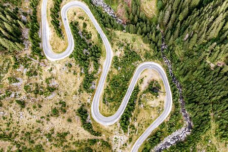 Winding road with a lot of turns, top view. Mountain river nearbyの写真素材