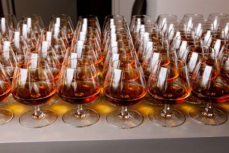 Stylish glasses with cognac or whiskey on table at event catering.の写真素材