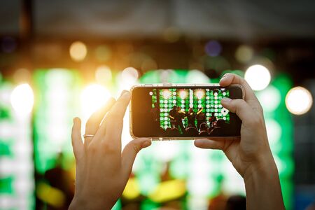 Mobile phone in hand during the shooting of a concert, light showの写真素材