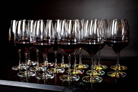 A lot of wine glasses with a cool delicious red wine at the bar or event catering. Alcohol background.の写真素材