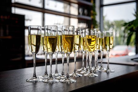 A lot of wine glasses with a cool delicious champagne or white wine at the bar or event catering. Alcohol background.の写真素材