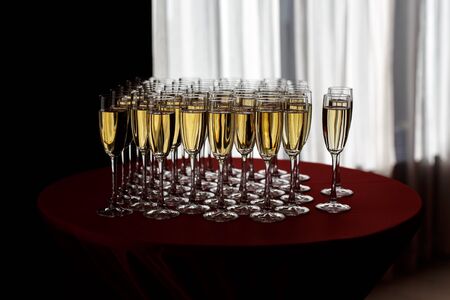 Elegant glasses with champagne standing in a row on serving table during party or celebrationの写真素材