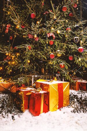 Beautiful decorated christmas tree with present boxes in a winter concept with snowの写真素材