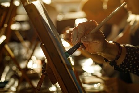 Hand of artist with brush painting picture, sunset lightの写真素材