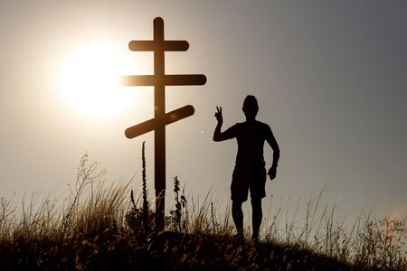 Silhouette of man near orthodox cross on the background of the sunset.の写真素材