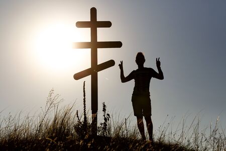 Silhouette of man near orthodox cross on the background of the sunset.の写真素材