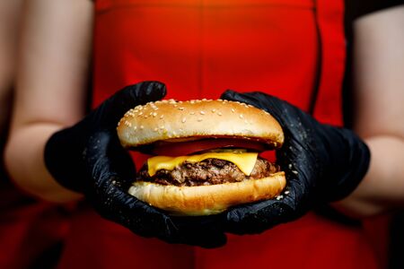 Man holds ready tasty burger in hands in black gloves.の写真素材