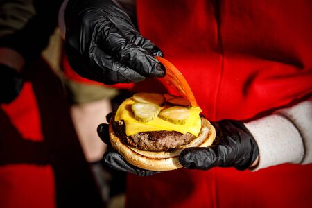 Chef makes a burger in black gloves. Picks up ingredientsの写真素材