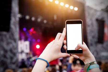 Recording concert by smartphone. Mobile phone in raised hands. Blank screenの写真素材