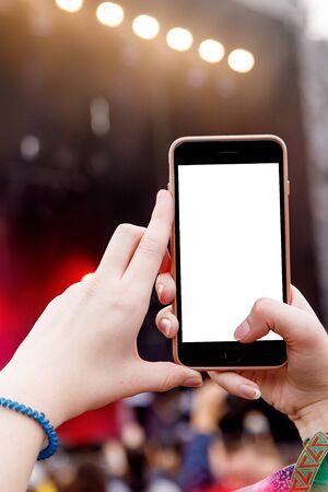 Smartphone in hands on music show. Empty screenの写真素材