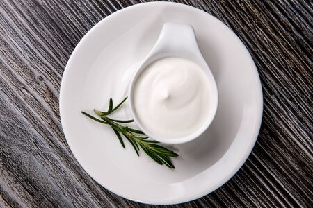 White plate full of sour cream on wooden table.の写真素材