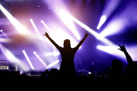 Silhouette of girl with raised hands enjoys the concert, music showの写真素材