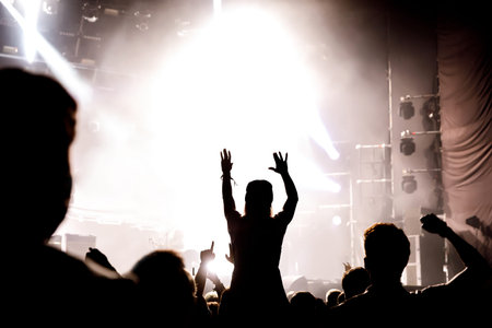 Silhouette of girl with raised hands enjoys the concert, music show