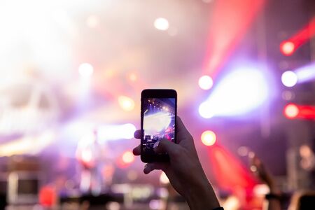 Man holding his smart phone and photographing concertの写真素材