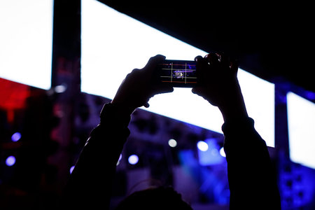People with mobile phone in hands shooting concert event.