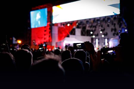 Silhouette of smartphone in hands of fan during music showの写真素材