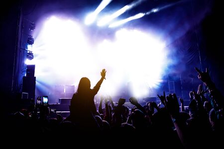 The audience at the concert enjoys. Silhouettes of raised hands and smartphonesの写真素材