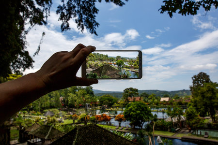 Photographing with smartphone in hand. Travel concept. Water Palace of Tirta Gangga in Baliの写真素材