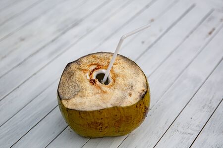 Coconut with a tube on a white table.の写真素材