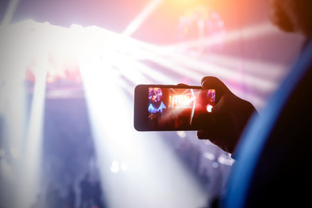 Silhouette of hand with smartphone on a concert. Record show