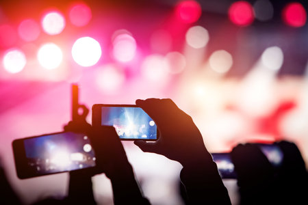 Man using smartphone to take a video at a concert.