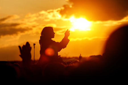 The young woman takes pictures of the festival on her smartphone. Black silhouette over sunsetの写真素材