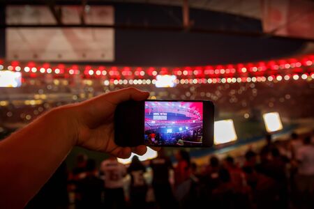 Using smartphone on a big sport stadium.の写真素材
