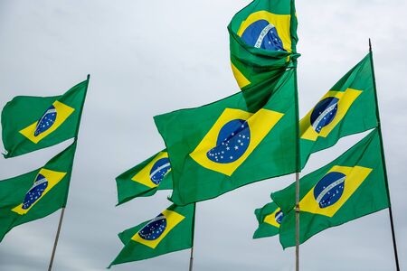 A lot of Brazilian flags on cloudy sky backgroundの写真素材