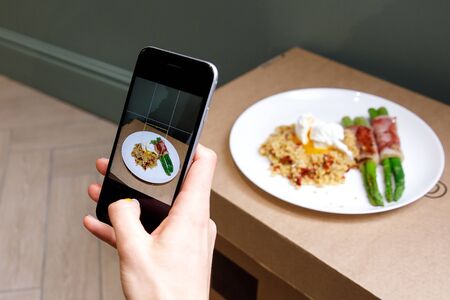 Taking a photo of porridge, vegetables, and bacon with a smartphoneの写真素材