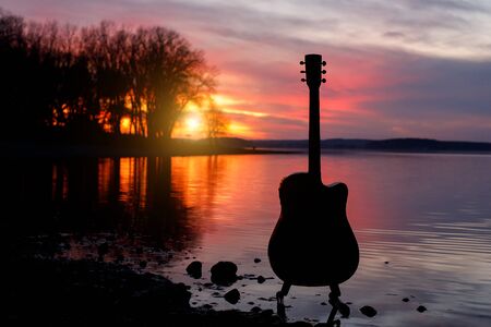 Guitar silhouette at sunset. Sea and trees on backgroundの写真素材