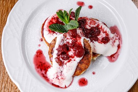 Cheese pancake, cheesecakes with sour cream, jam, and mint on a plate. Morning breakfastの写真素材