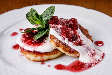 Cheese pancake, cheesecakes with sour cream, jam, and mint on a plate. Morning breakfastの写真素材