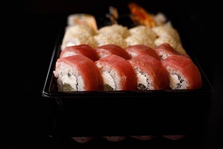 Sushi delivery. Set of rolls in a disposable box on a black backgroundの写真素材