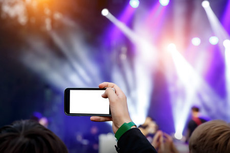 Live stream for social networks at a concert. Using a smartphone camera. White smartphone blank...