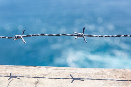 Barbed wire closeup. Blue sea on backgroundの写真素材