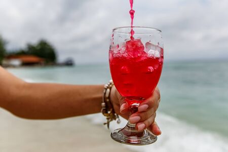 Pouring red soda beverage on summer beachの写真素材