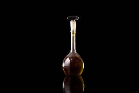 Old dusty medicine flask on a black background with reflectionの写真素材