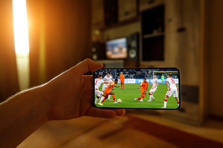 Minsk. Belarus - 20.04.2020: Watching football game at home via smartphone. Broadcasting soccer from...