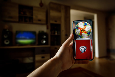 Minsk. Belarus - 20.04.2020: Watching EURO football game at home via smartphone. Broadcasting from the stadium.のeditorial素材