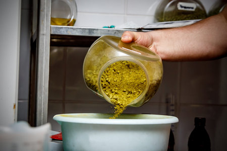 Spill granulated hops from a glass jar into a basinの写真素材