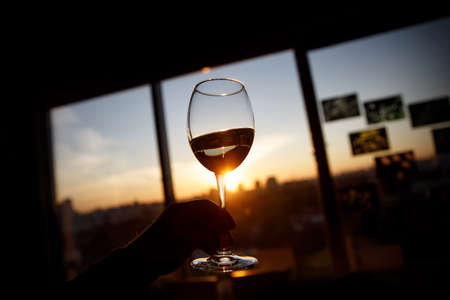 Wine glass in a hand over sunsetの写真素材