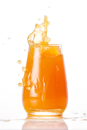 The glass of splashing fruit juice isolated on white backgroundの写真素材