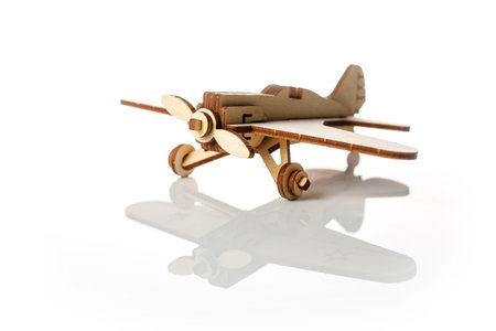 Small wooden airplane on a white background with reflectionの写真素材