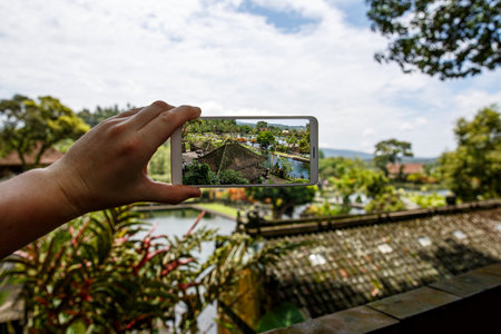 Photographing with smartphone in hand. Travel concept. Water Palace of Tirta Gangga in Baliの写真素材
