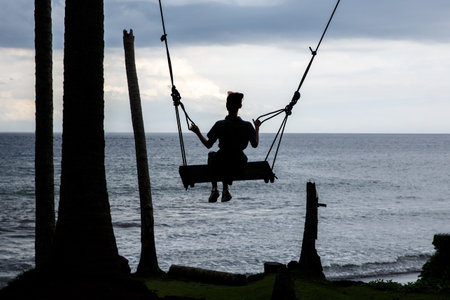 Silhouette of a girl on a swingの写真素材