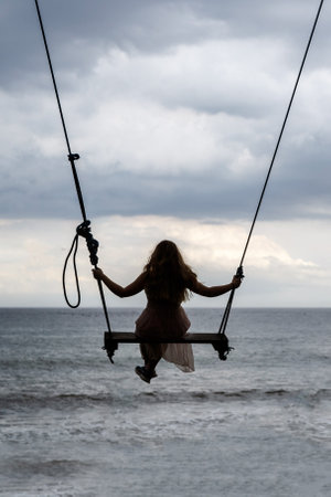 Silhouette of a girl on a swingの写真素材